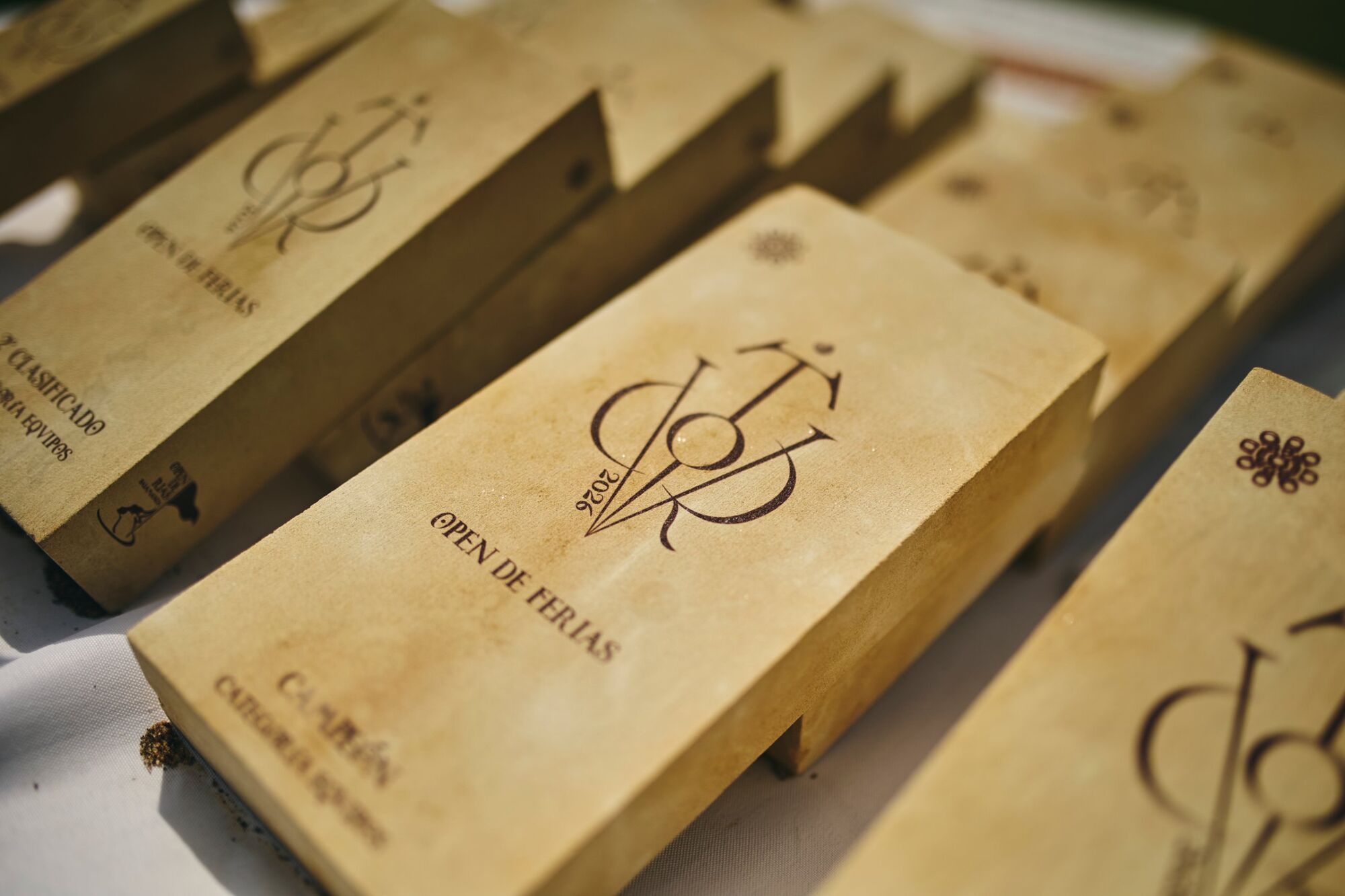 Trofeos de piedra grabados con el monograma del Open de Ferias alineados sobre una mesa